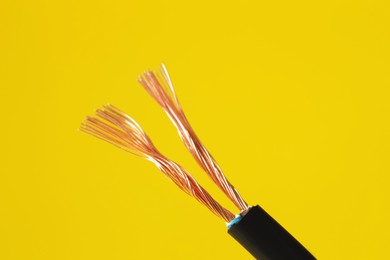 Photo of Black stripped electrical wire on yellow background, closeup