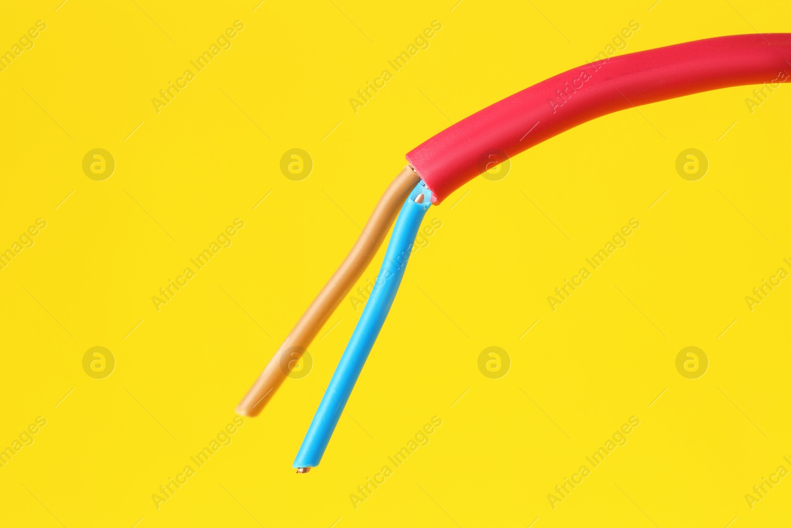 Photo of Red stripped electrical wire on yellow background, closeup