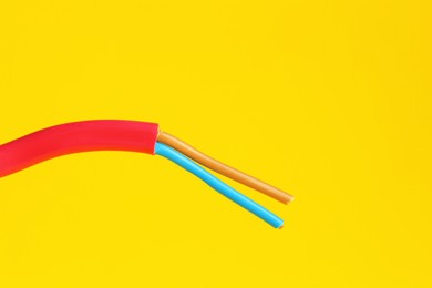 Photo of Red stripped electrical wire on yellow background, closeup