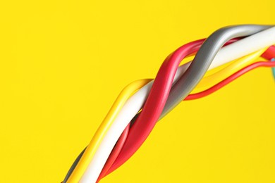 Photo of Many electrical wires on yellow background, closeup. Space for text