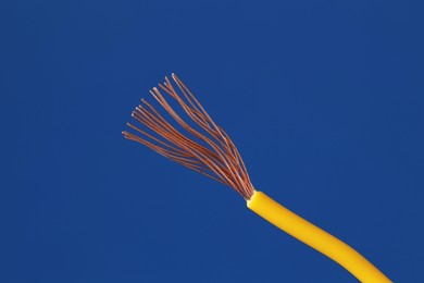 Photo of Yellow stripped electrical wire on blue background, closeup