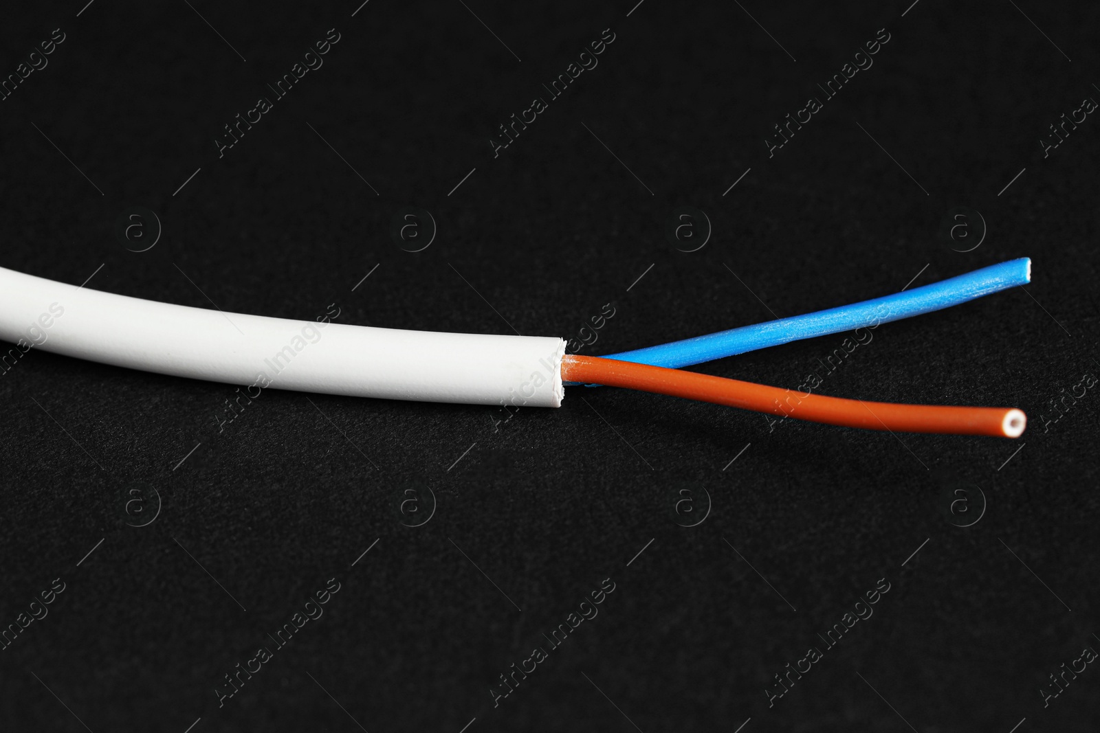 Photo of White stripped electrical wire on black background, closeup