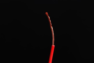 Photo of Red stripped electrical wire on black background, closeup