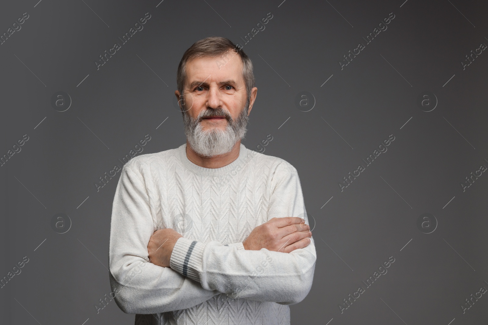 Photo of Portrait of mature man with crossed arms on grey background