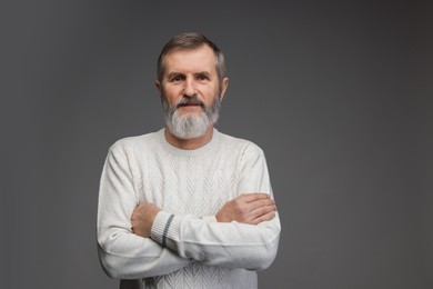 Portrait of mature man with crossed arms on grey background