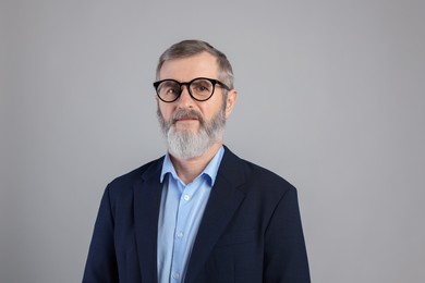 Portrait of mature man in glasses on grey background