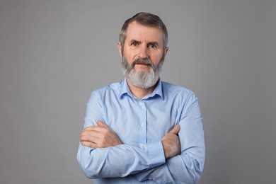 Photo of Portrait of mature man with crossed arms on grey background