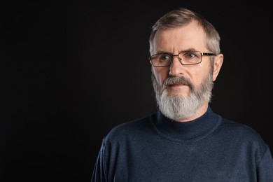 Photo of Portrait of mature man in glasses on black background, space for text