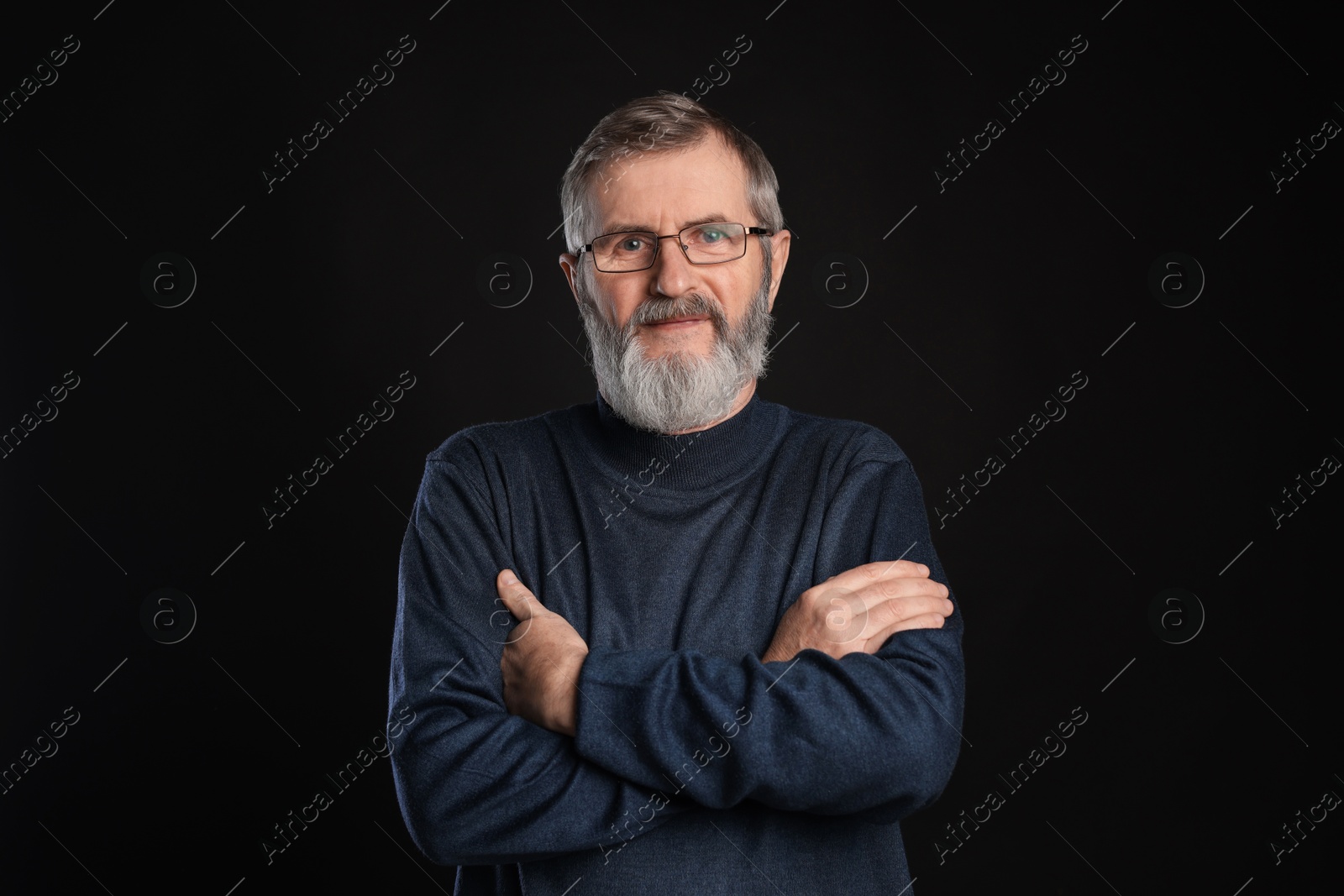 Photo of Portrait of mature man with crossed arms on black background