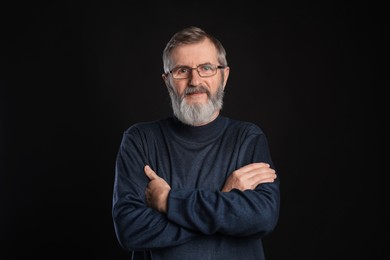 Photo of Portrait of mature man with crossed arms on black background