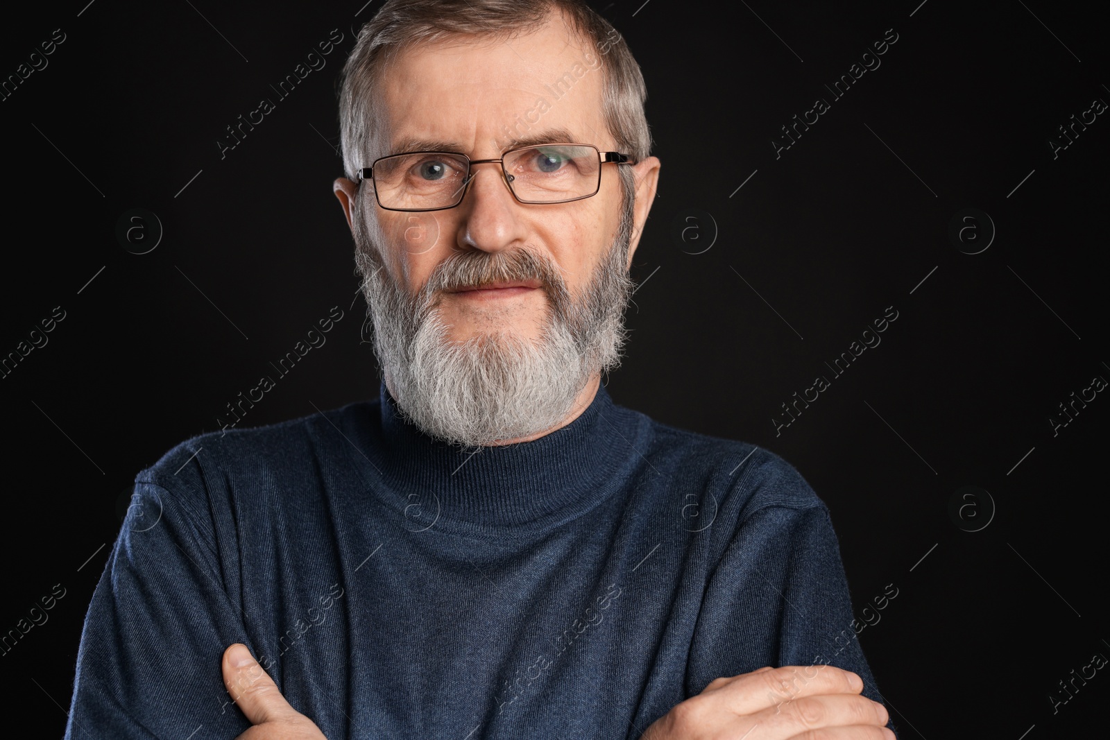 Photo of Portrait of mature man with crossed arms on black background