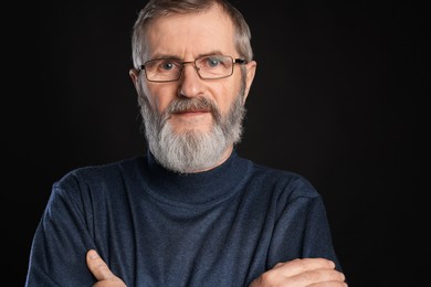 Photo of Portrait of mature man with crossed arms on black background