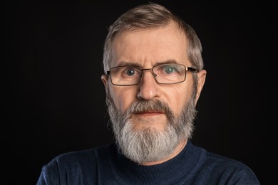 Photo of Portrait of mature man in glasses on black background