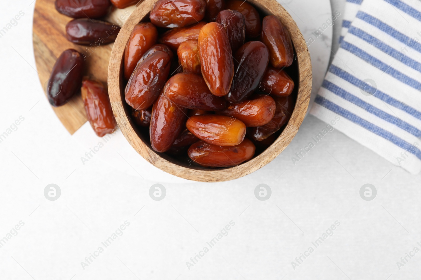 Photo of Tasty dried dates in bowl on white table, top view. Space for text