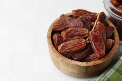 Photo of Tasty dried dates on white tiled table, closeup. Space for text