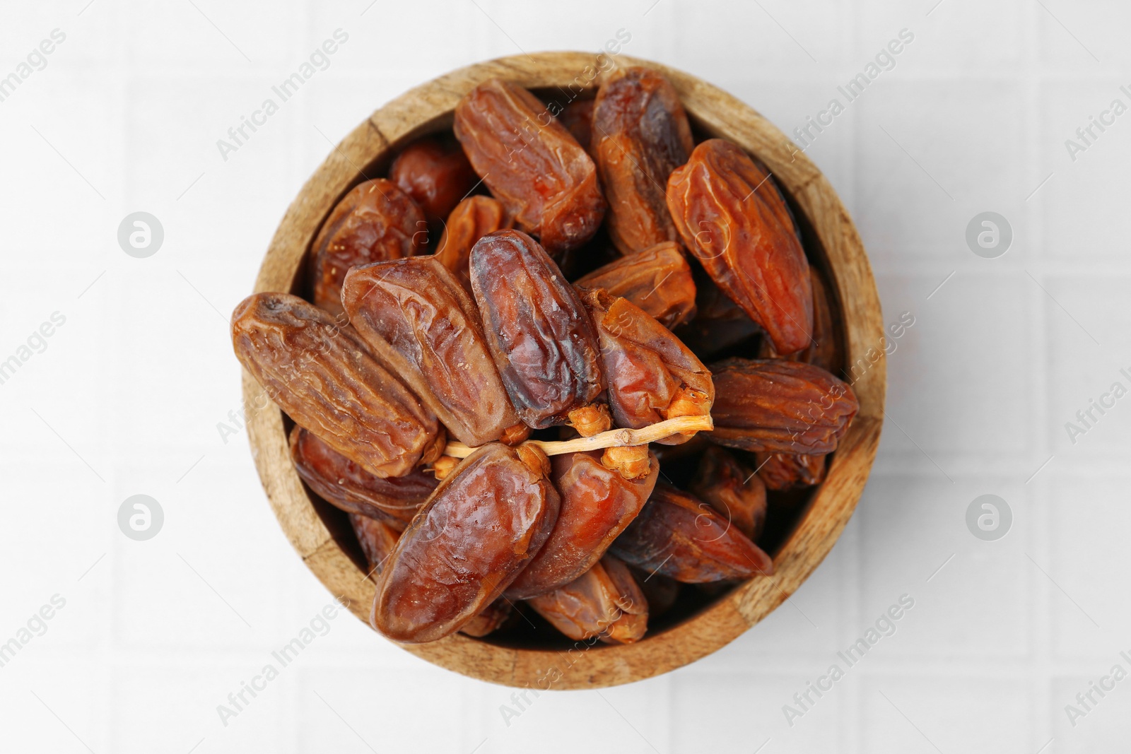 Photo of Tasty dried dates on white tiled table, top view