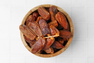 Photo of Tasty dried dates on white tiled table, top view