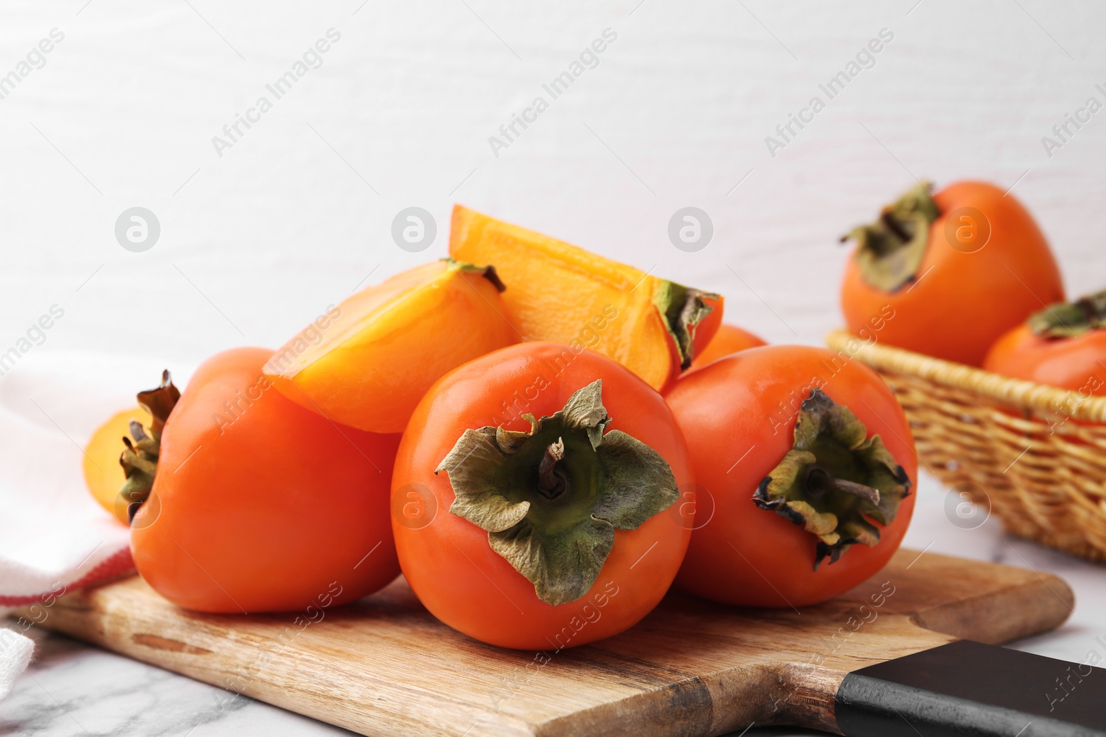 Photo of Whole and cut ripe persimmons on table, closeup