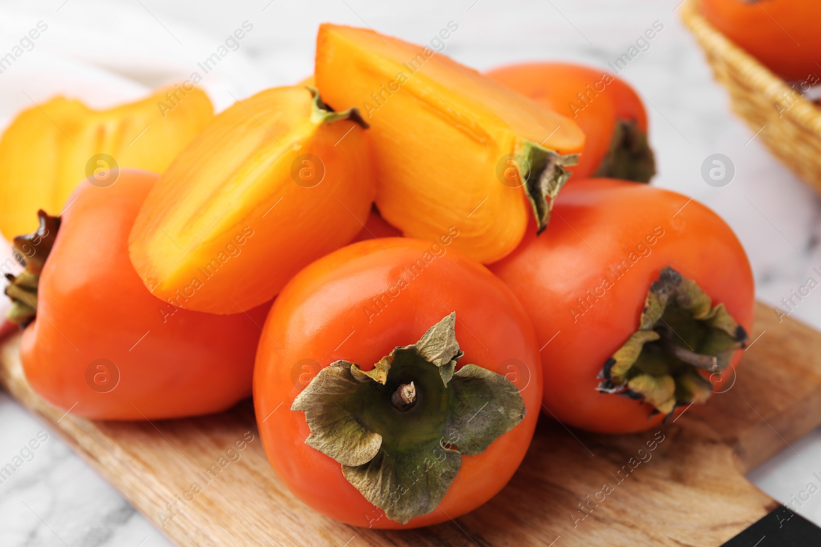 Photo of Whole and cut ripe persimmons on table, closeup