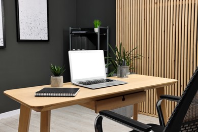 Photo of Comfortable workplace with modern laptop on wooden table indoors