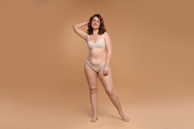 Beautiful woman in underwear on dark beige background. Cellulite problem