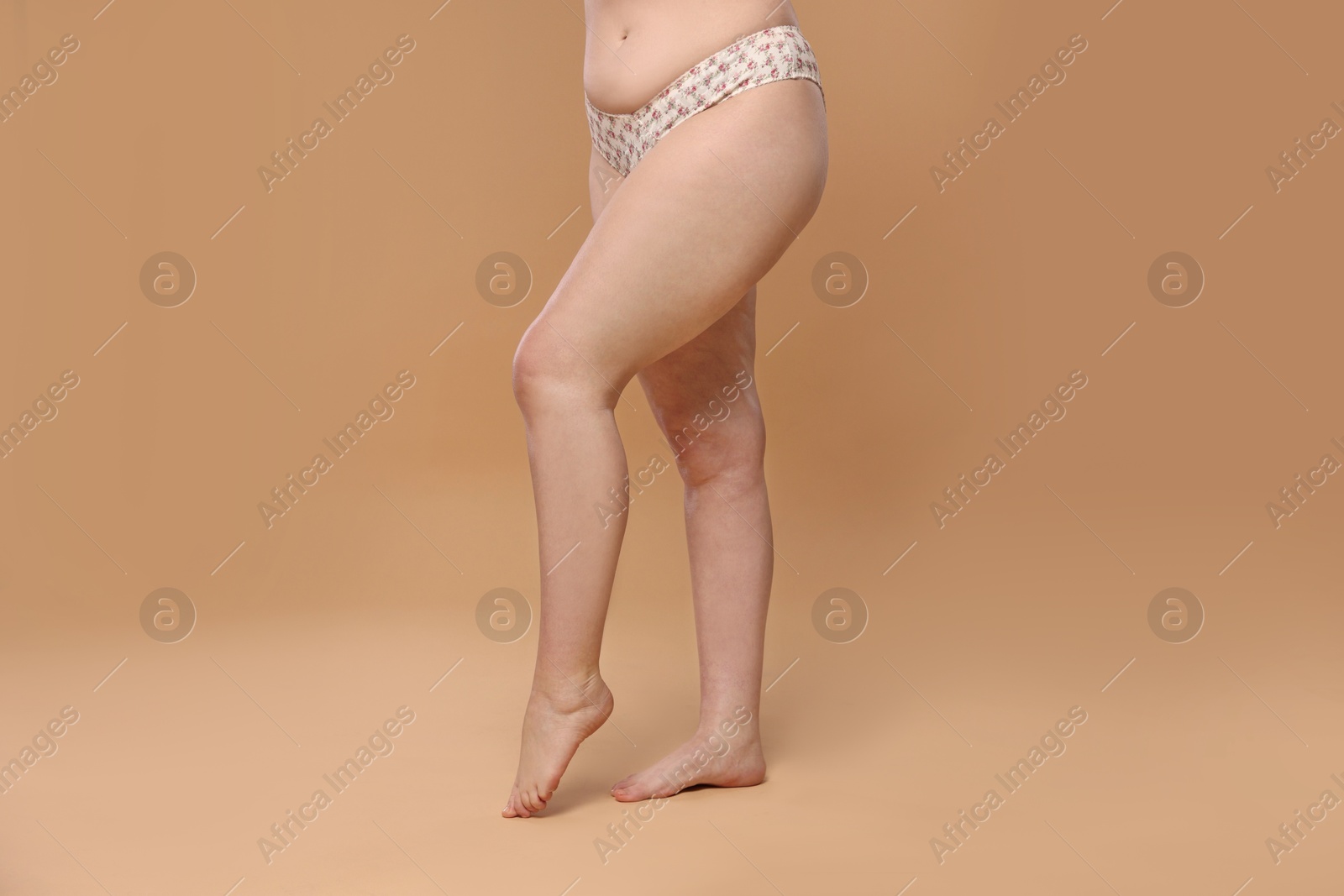 Photo of Woman with cellulite on dark beige background, closeup