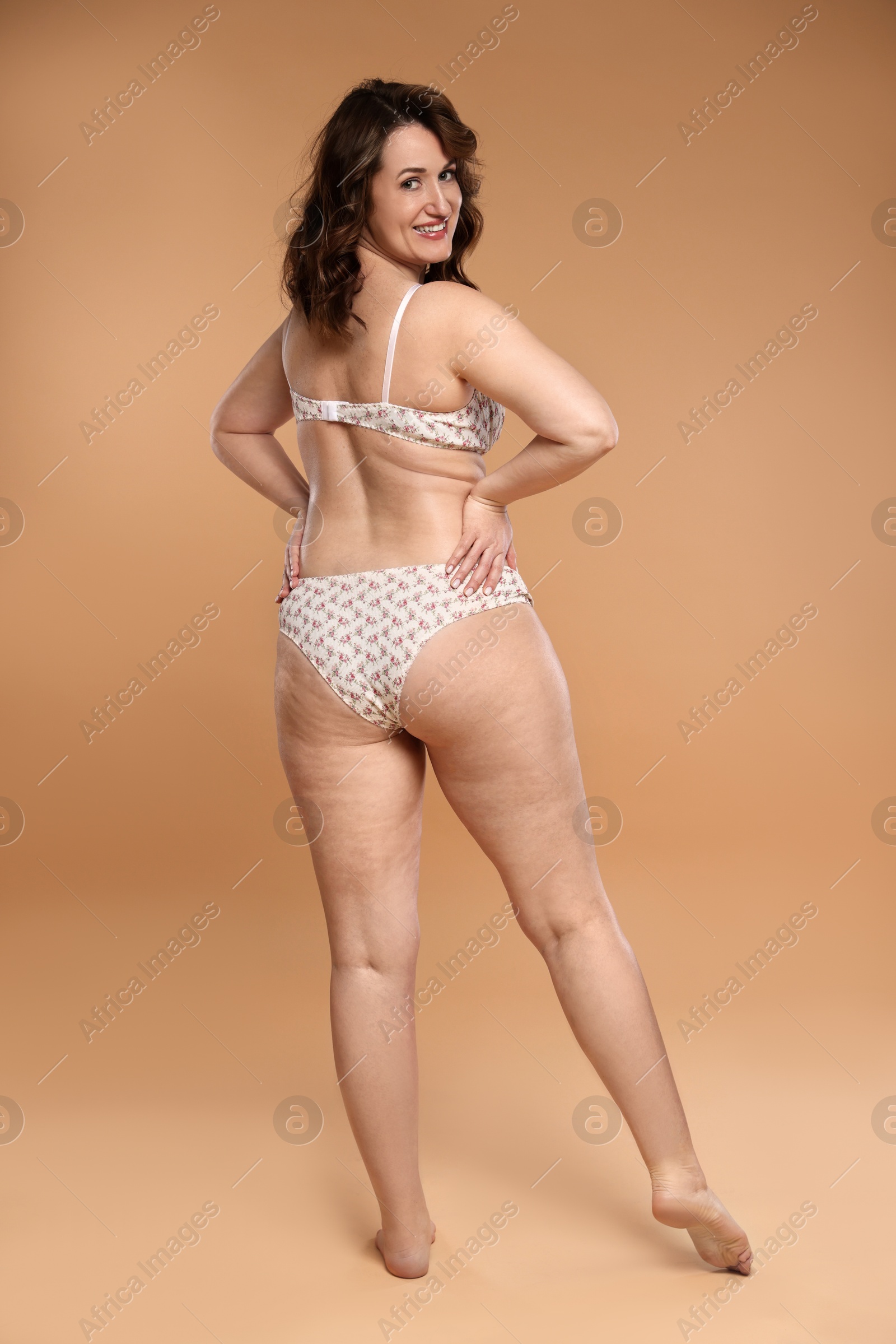 Photo of Beautiful woman in underwear on dark beige background. Cellulite problem