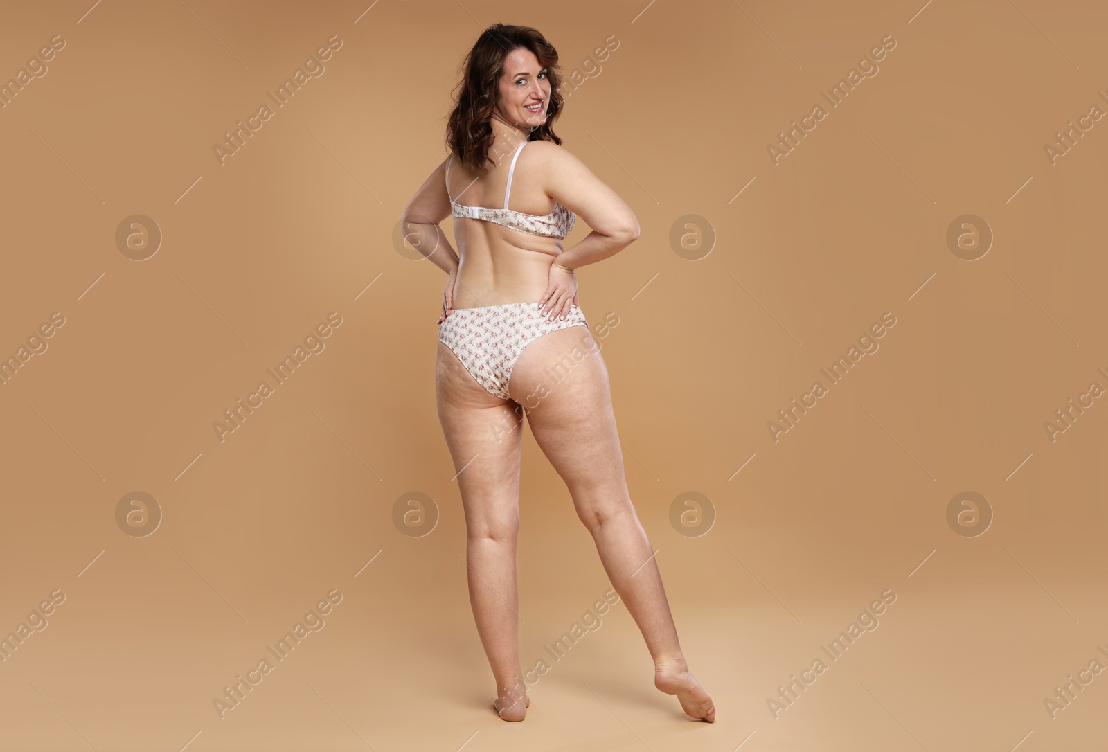 Photo of Beautiful woman in underwear on dark beige background. Cellulite problem