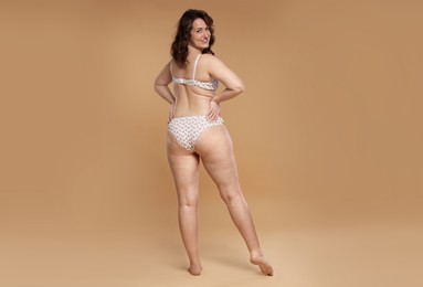 Photo of Beautiful woman in underwear on dark beige background. Cellulite problem