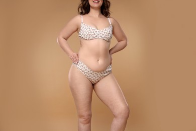 Woman with cellulite on dark beige background, closeup