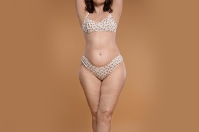 Photo of Woman with cellulite on dark beige background, closeup