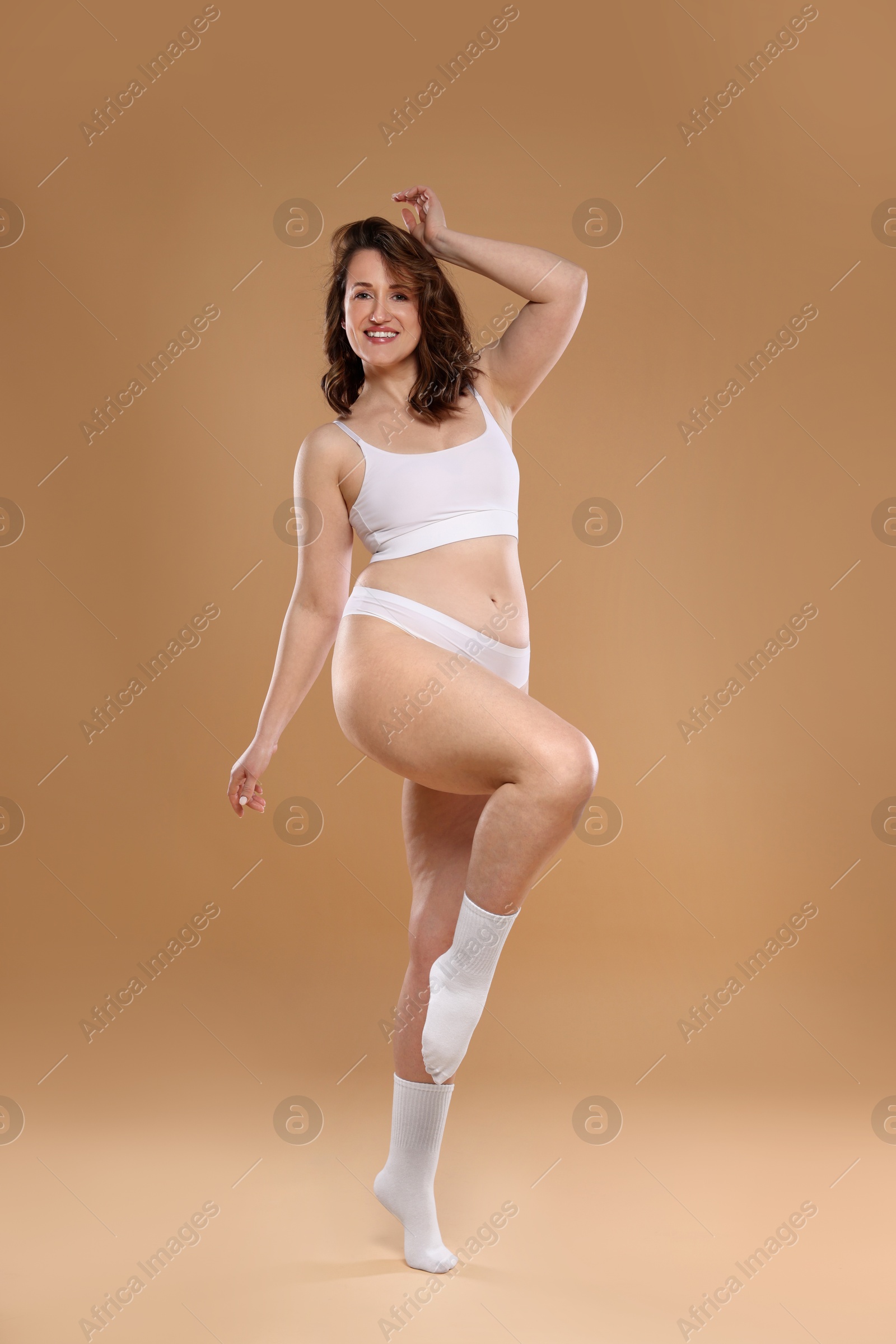 Photo of Beautiful woman in underwear on dark beige background. Cellulite problem