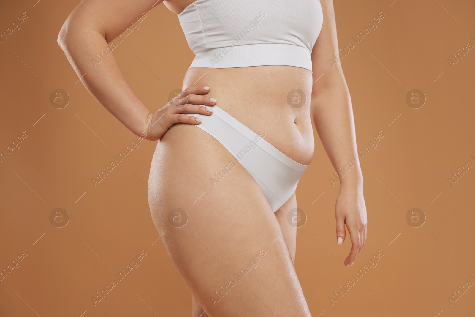 Photo of Woman with cellulite on light brown background, closeup