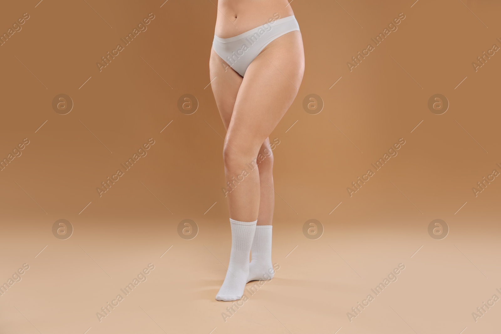 Photo of Woman with cellulite on dark beige background, closeup