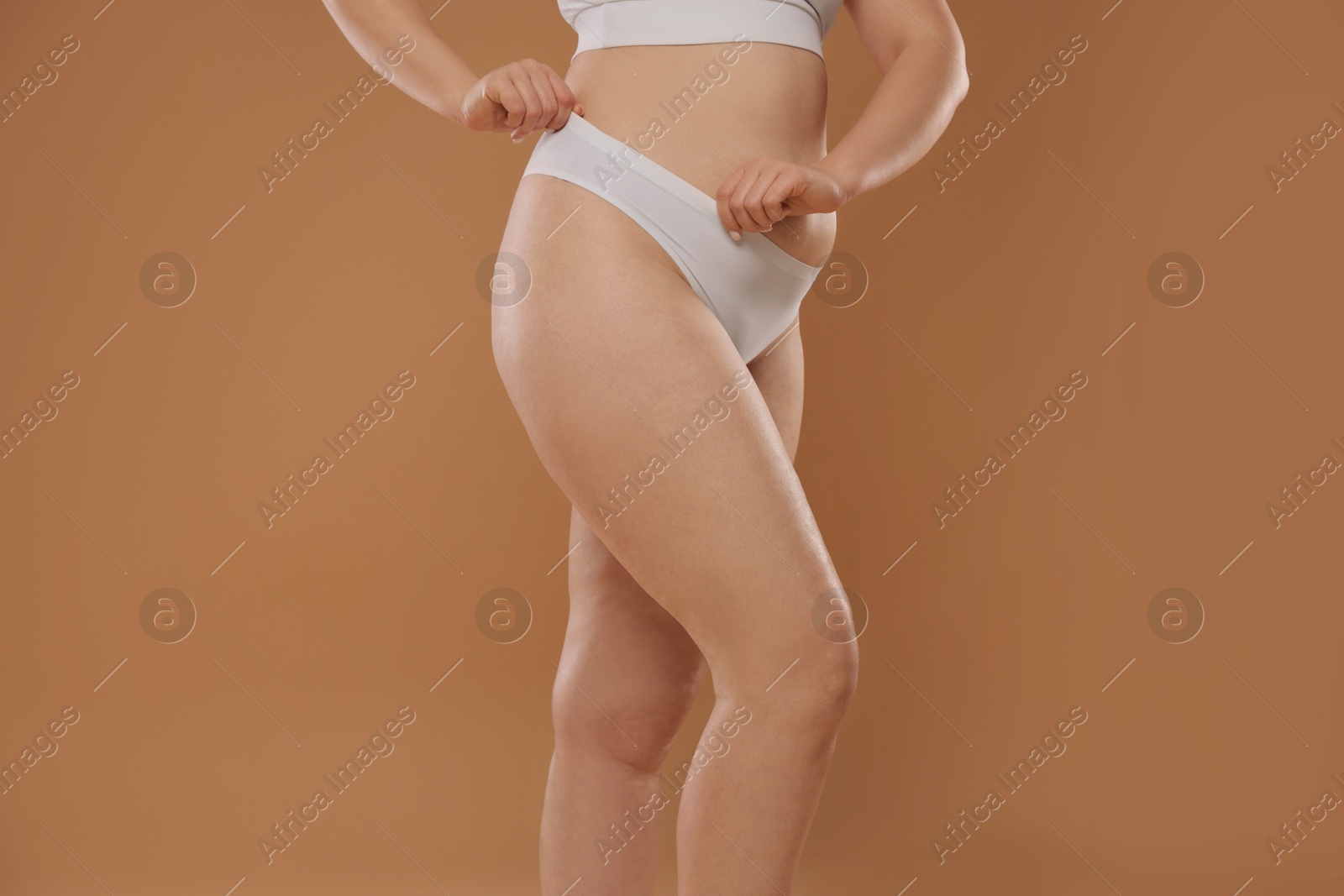 Photo of Woman with cellulite on light brown background, closeup