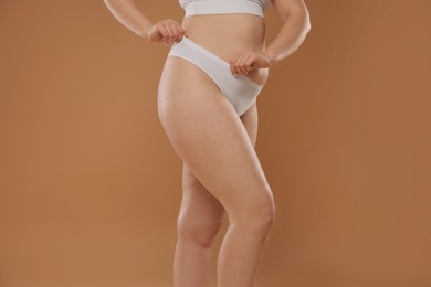 Photo of Woman with cellulite on light brown background, closeup