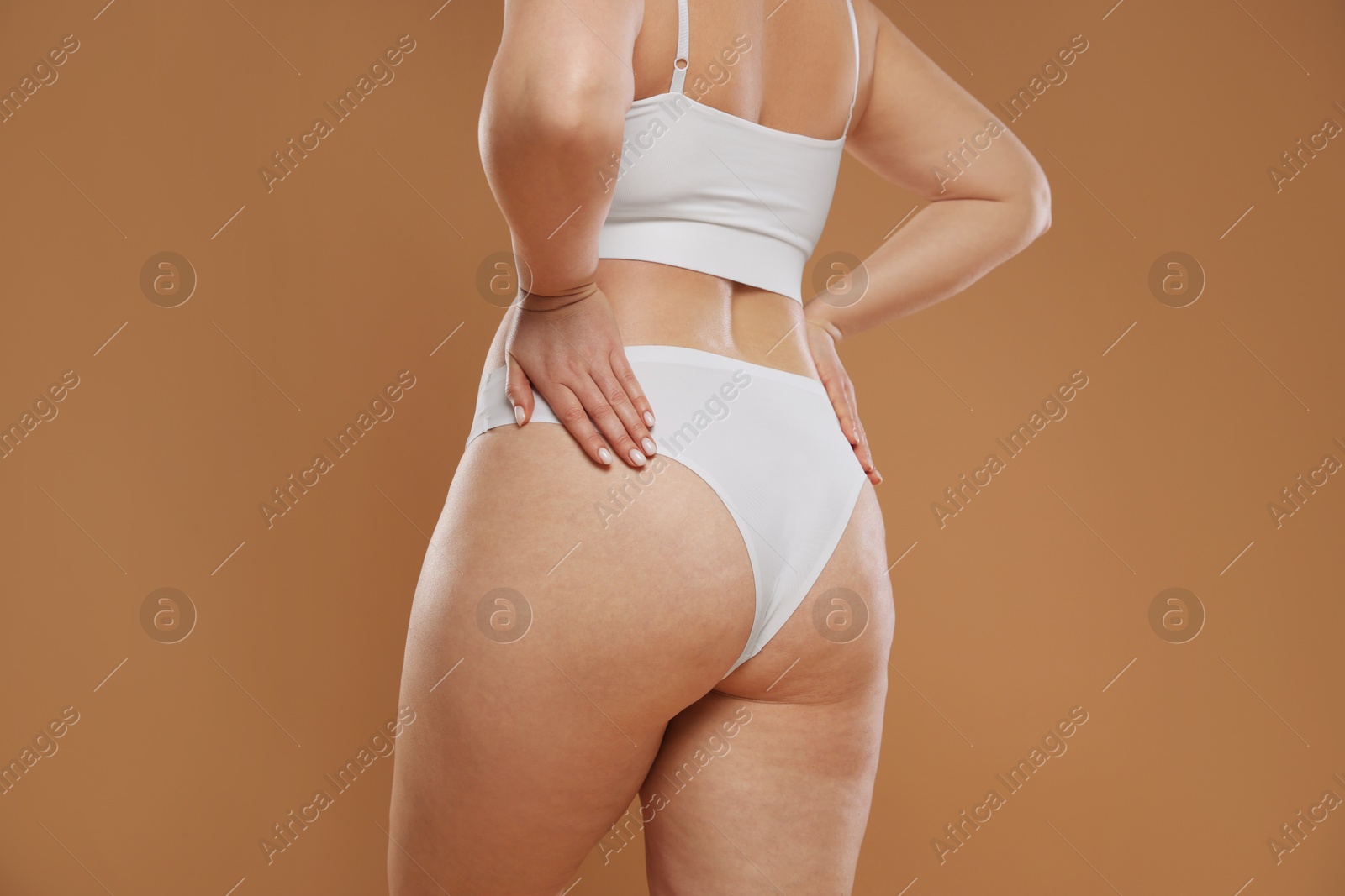 Photo of Woman with cellulite on light brown background, closeup