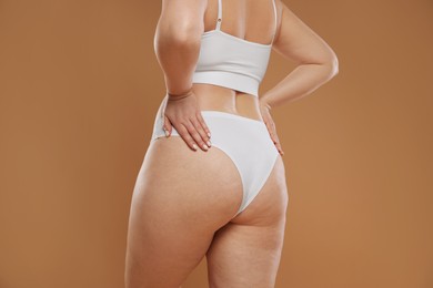 Photo of Woman with cellulite on light brown background, closeup