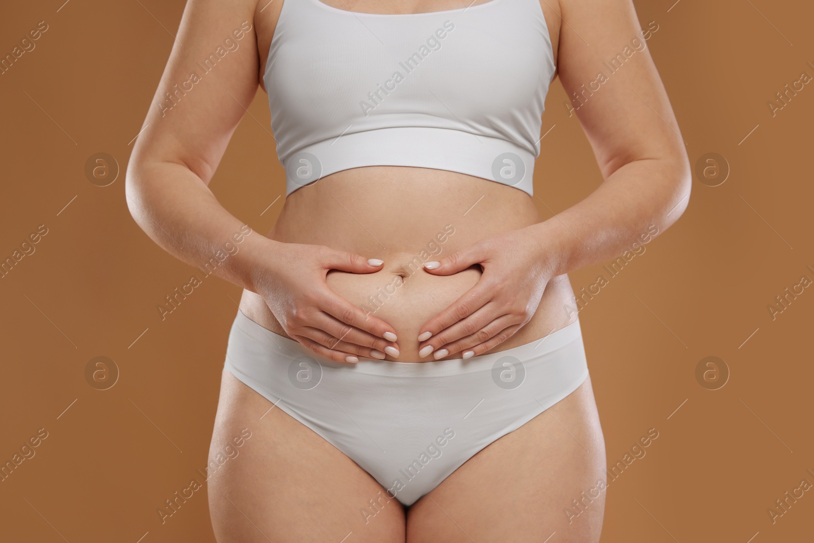 Photo of Woman with cellulite on light brown background, closeup