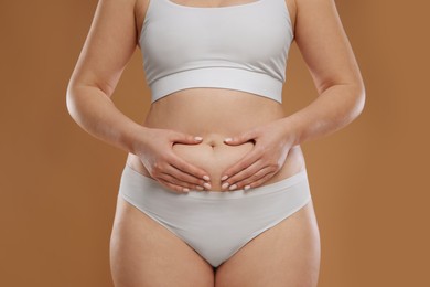 Photo of Woman with cellulite on light brown background, closeup