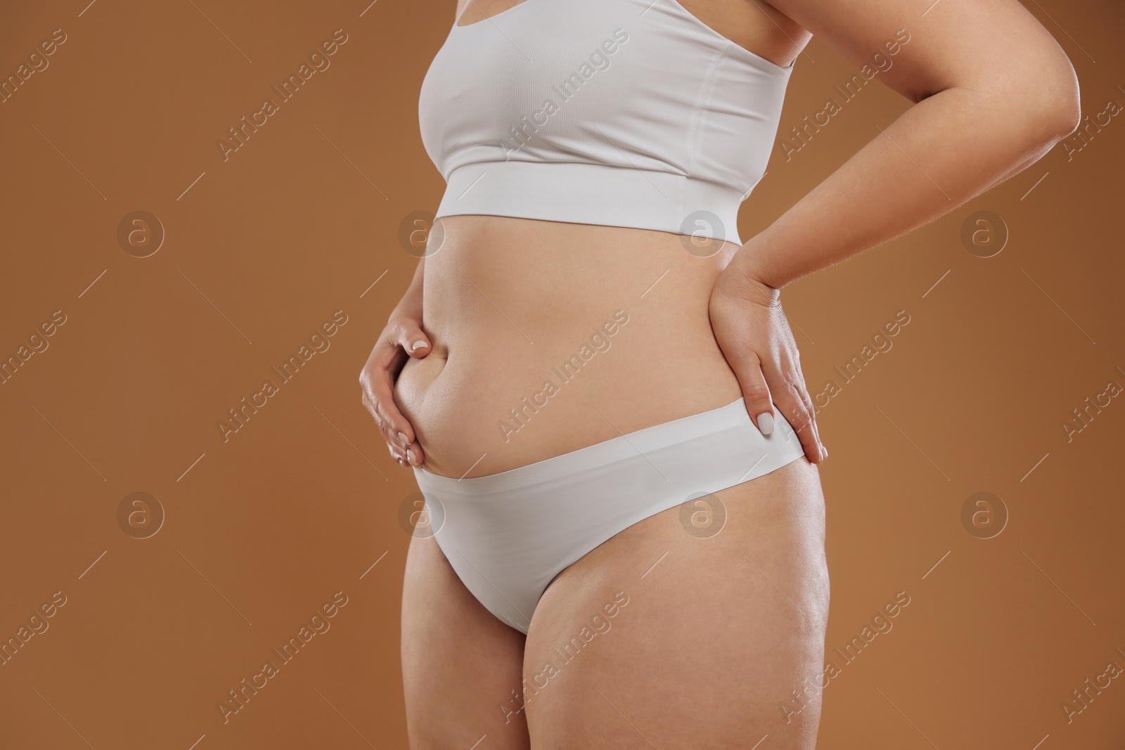 Photo of Woman with cellulite on light brown background, closeup