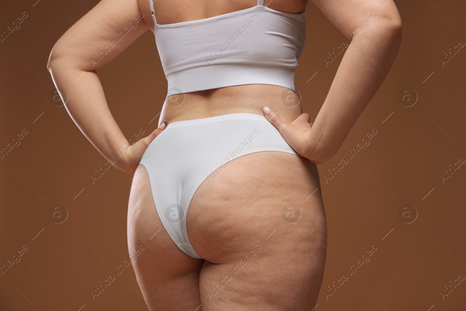 Photo of Woman with cellulite on brown background, closeup