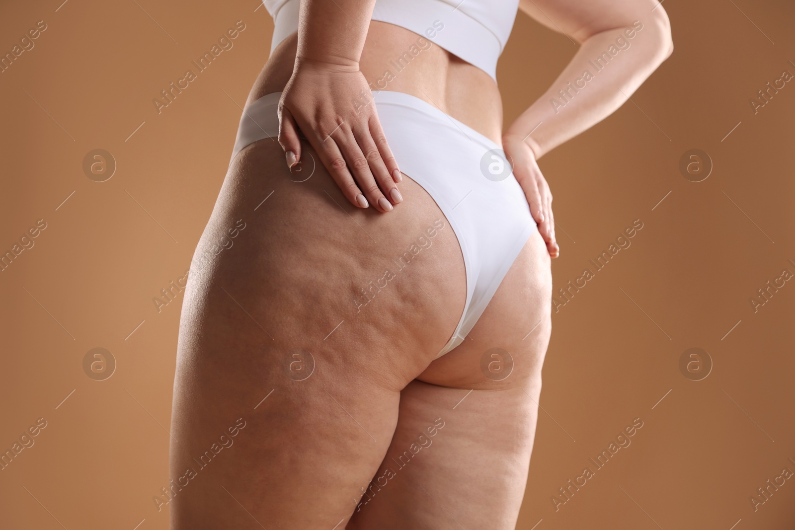 Photo of Woman with cellulite on light brown background, closeup