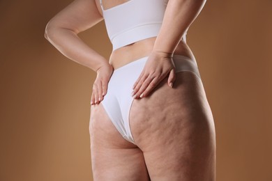 Photo of Woman with cellulite on light brown background, closeup