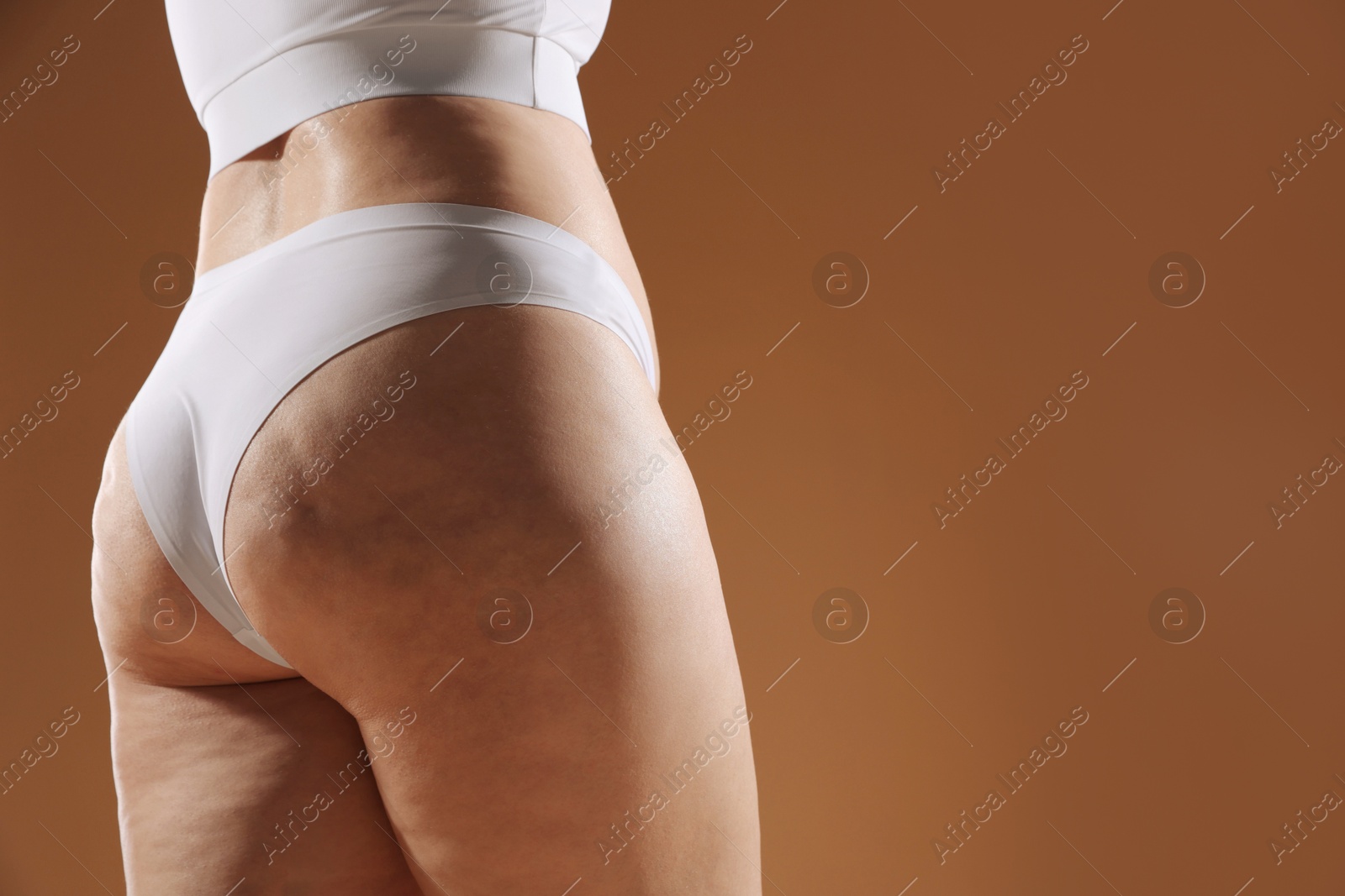 Photo of Woman with cellulite problem on brown background, closeup. Space for text