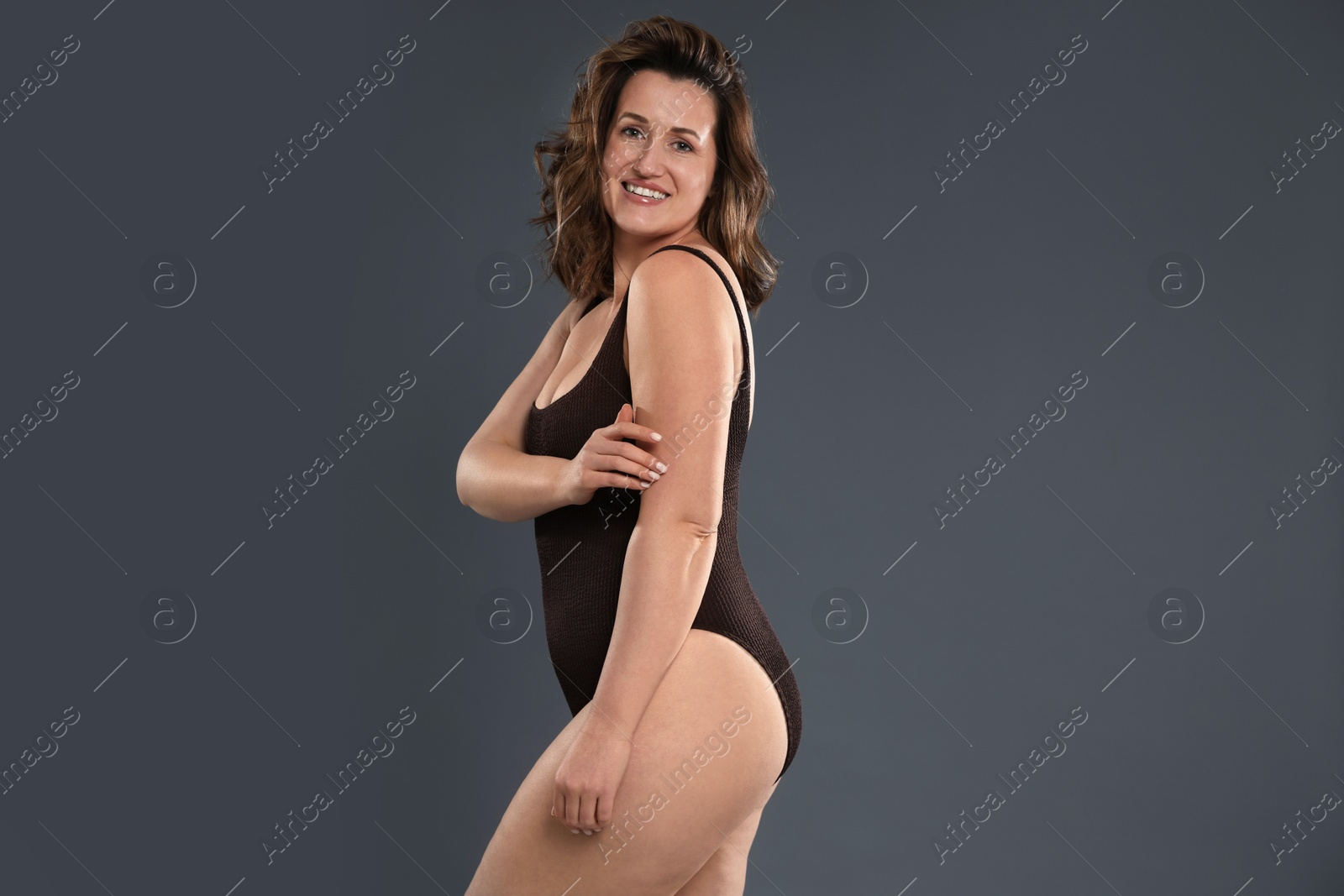 Photo of Beautiful woman in bodysuit on dark grey background. Cellulite problem