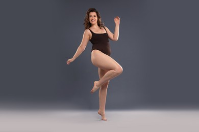 Beautiful woman in bodysuit on dark grey background. Cellulite problem