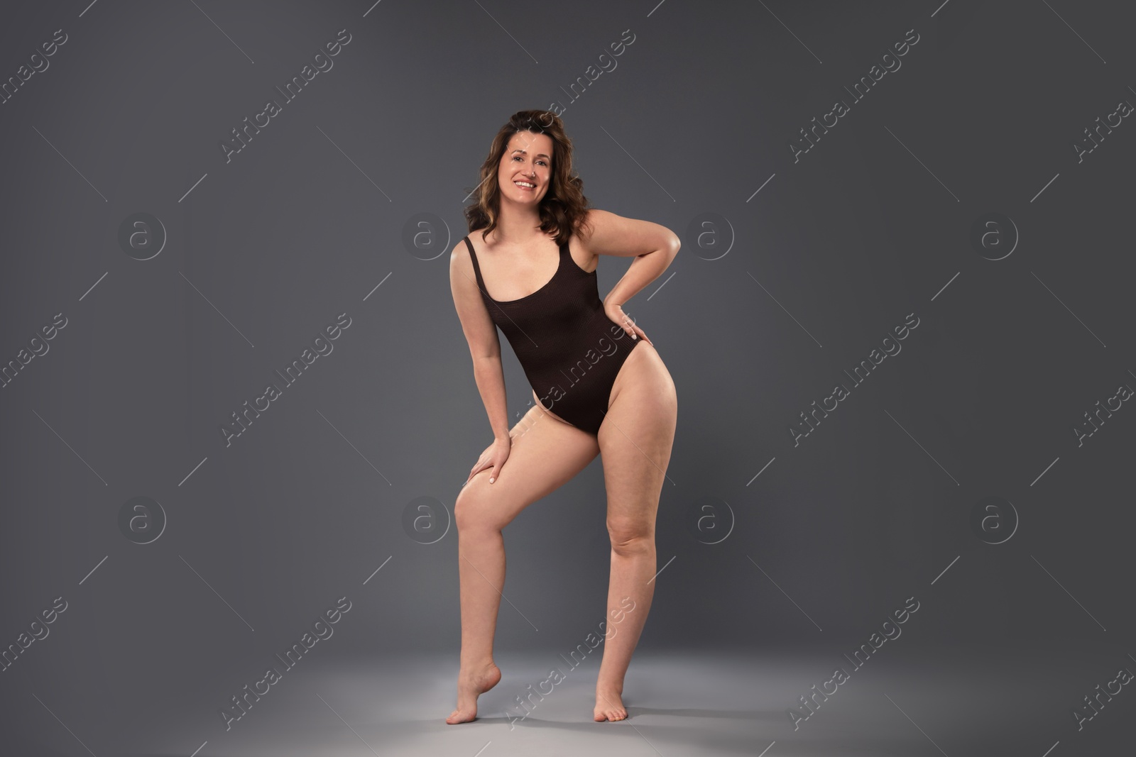 Photo of Beautiful woman in bodysuit on dark grey background. Cellulite problem