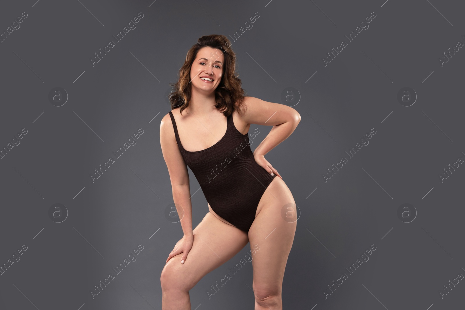 Photo of Beautiful woman in bodysuit on dark grey background. Cellulite problem