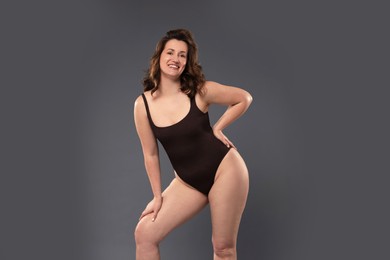 Photo of Beautiful woman in bodysuit on dark grey background. Cellulite problem